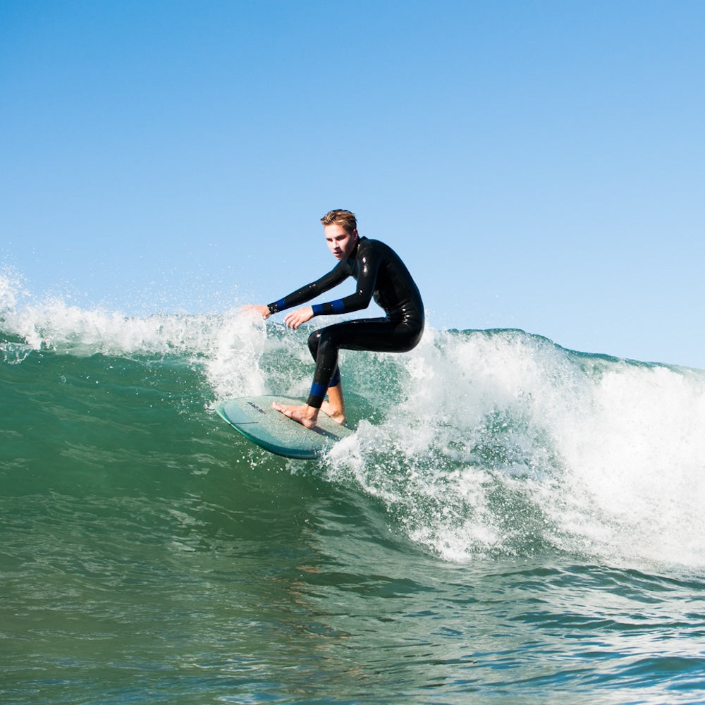 Person surfing on a wave with clear blue sky