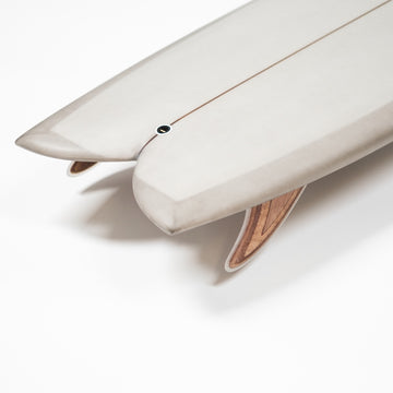 Close-up of a white surfboard with a wooden fin on a white background